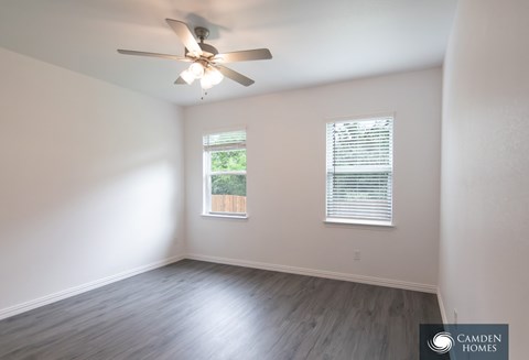 A Camden Homes branded empty room with a ceiling fan and a window with blinds.
