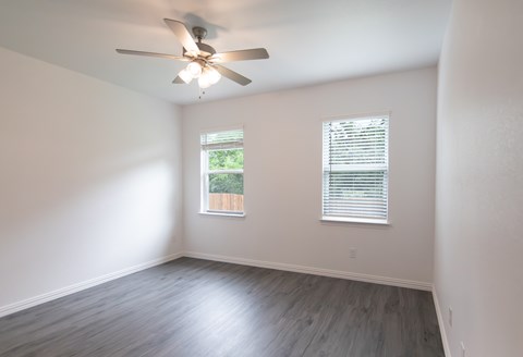 A room with a ceiling fan and a window with blinds.