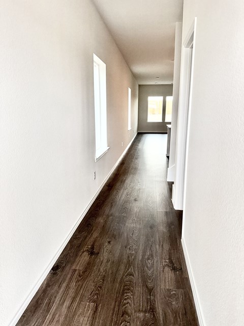 A long hallway with wood floors and white walls.