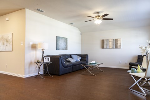 A living room with a black couch and a ceiling fan.