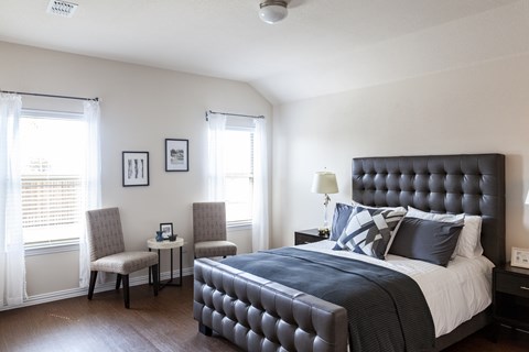 A bedroom with a large bed and a chair by the window.