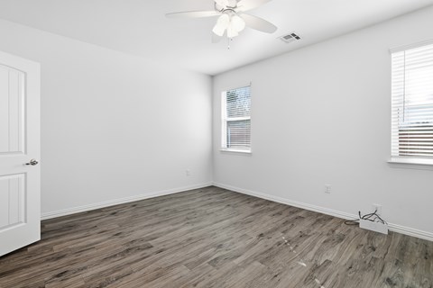 A room with a ceiling fan and wooden flooring.