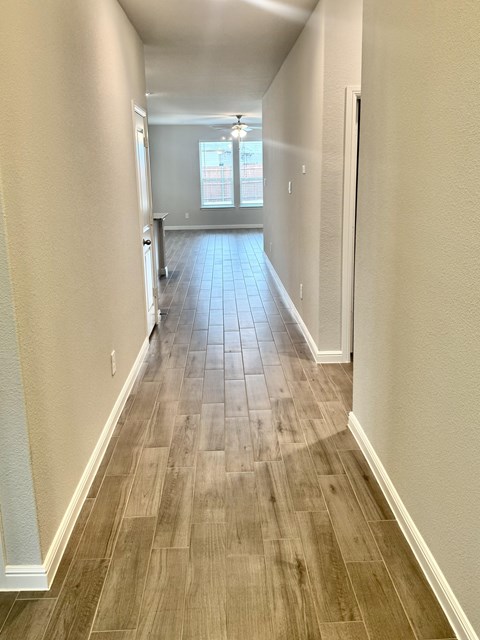 A long hallway with wood flooring and white walls.