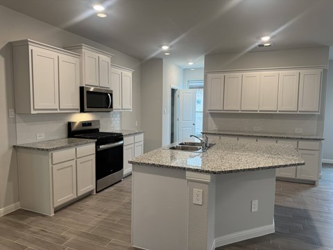 A kitchen with a granite countertop and white cabinets.