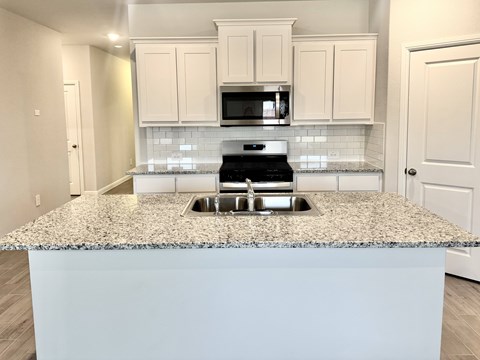 A kitchen with a granite countertop and white cabinets.