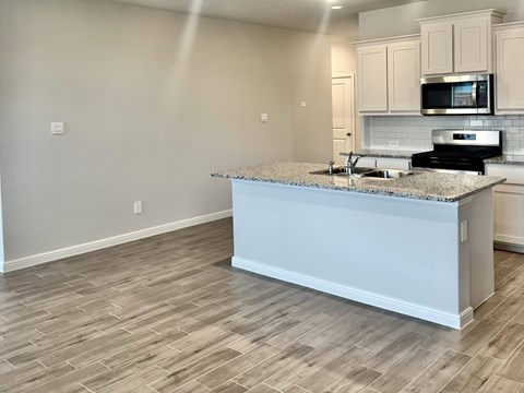 A kitchen with a granite countertop and a microwave above it.