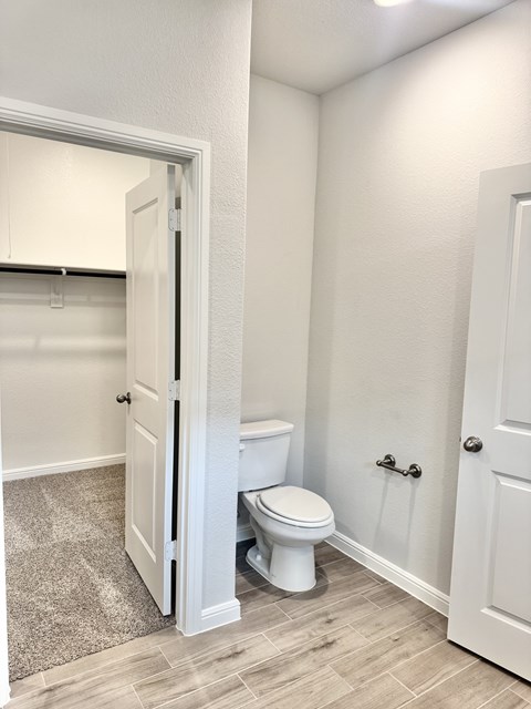 A white toilet in a bathroom with a white door.
