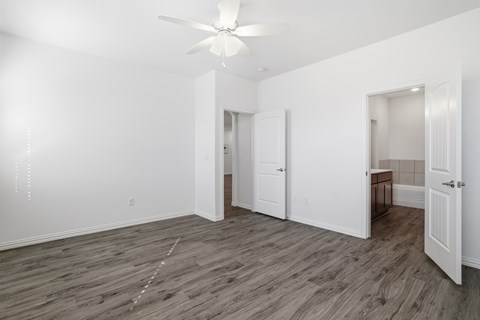 A room with a ceiling fan and wooden flooring.