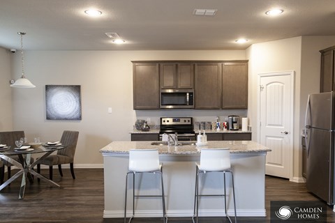 A kitchen with a table and chairs in front of it.