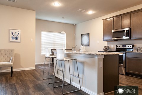 A kitchen with a white counter top and a white chair.