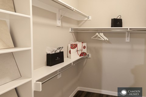 A white closet with a black speaker on the top shelf.
