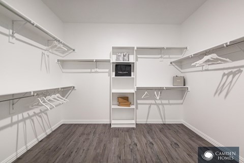 A white closet with a shelf and clothes hanging.
