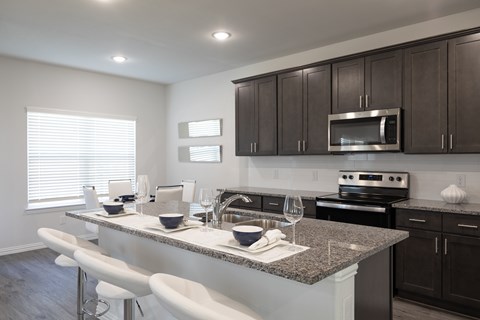 A modern kitchen with dark brown cabinets and white countertops.