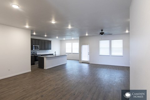 A spacious room with wooden floors and a ceiling fan.