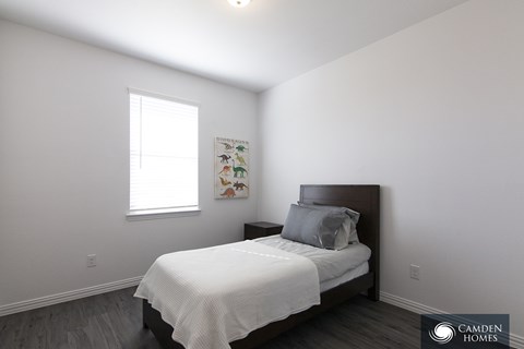 A bedroom with a bed, pillow, and a picture on the wall.