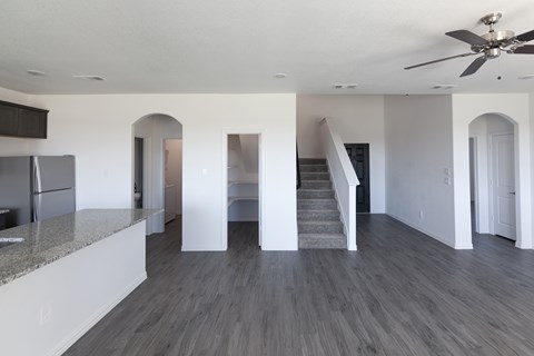 A spacious kitchen with a refrigerator and a staircase leading to the upper floor.