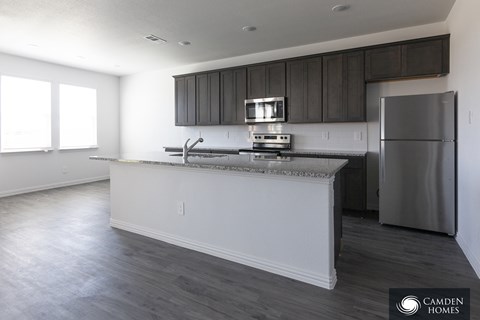 A kitchen with a stainless steel refrigerator and a countertop with a sink.