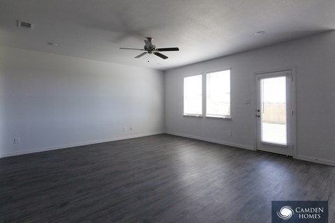 A room with a ceiling fan and two windows.