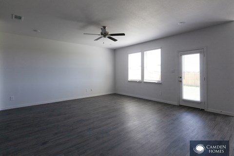 A room with a ceiling fan and two windows.
