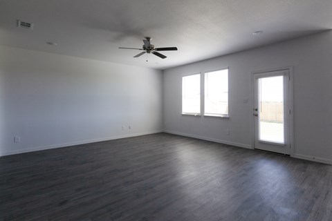 A room with a ceiling fan and two windows.