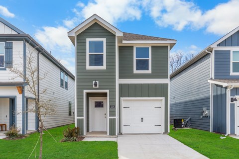 A modern house with a grey garage door is in front of a white house.