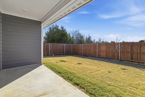 A backyard with a wooden fence and a grey garage door.