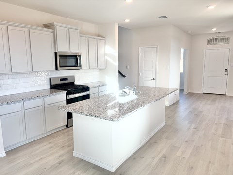 A kitchen with white cabinets and a granite countertop.