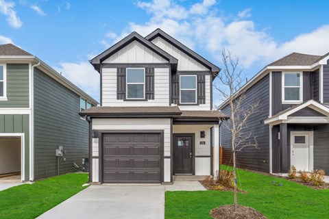 A house with a grey garage door is in front of two other houses.
