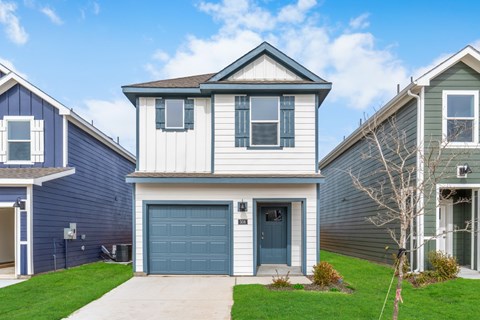 A house with a blue garage door is in front of two other houses.