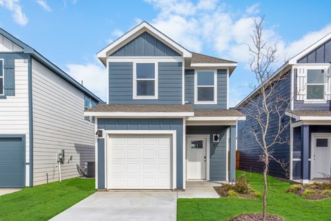 A house with a grey garage door is in front of other houses.