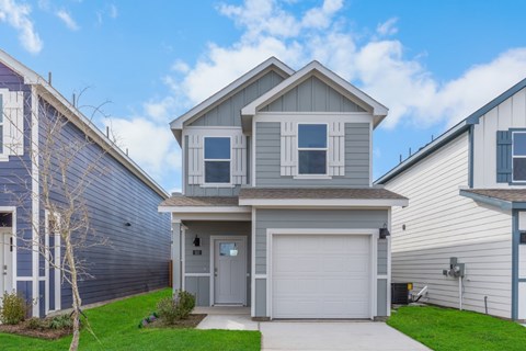 A two-story house with a garage is surrounded by other houses.