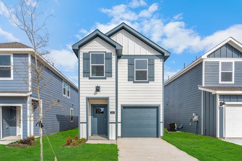 A house with a grey garage door is in front of two other houses.