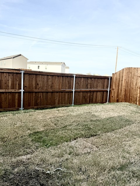 A backyard with a wooden fence and a grassy area.