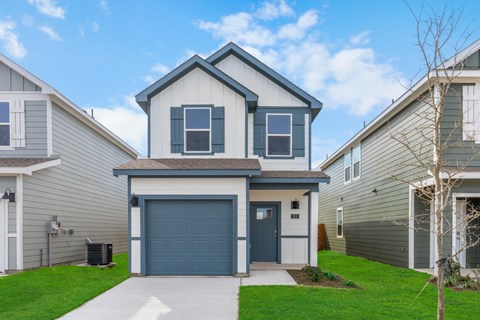 A house with a grey garage door is in front of other houses.