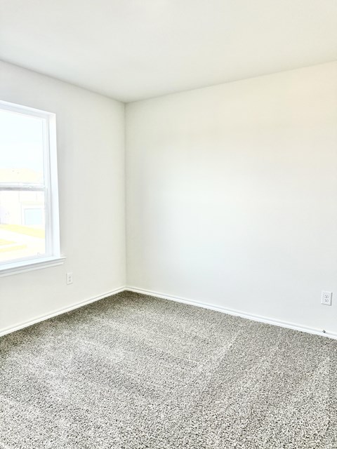 A room with a carpeted floor and a window.
