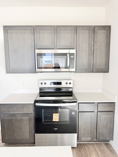 A modern kitchen with a stove, oven, and microwave above it.