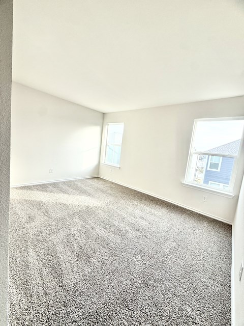 A room with a carpeted floor and a window.