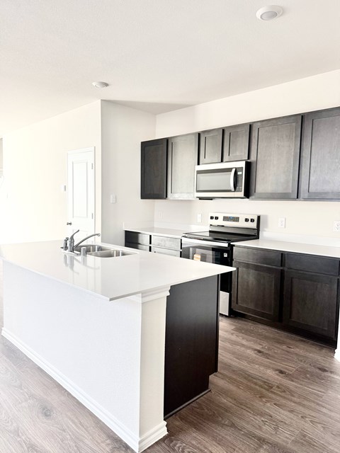 A modern kitchen with a white island and black cabinets.