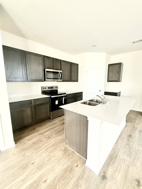 A kitchen with a white counter top and black cabinets.