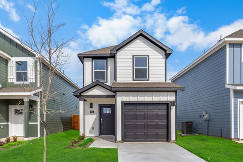 A house with a grey garage door is in front of two other houses.