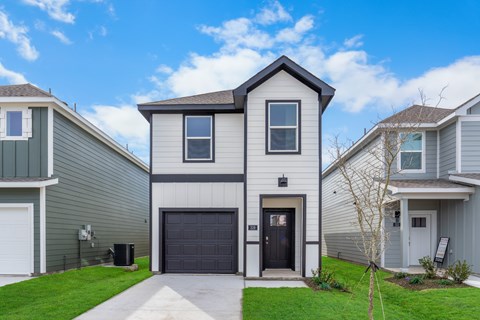 A modern two-story house with a garage door and a driveway.
