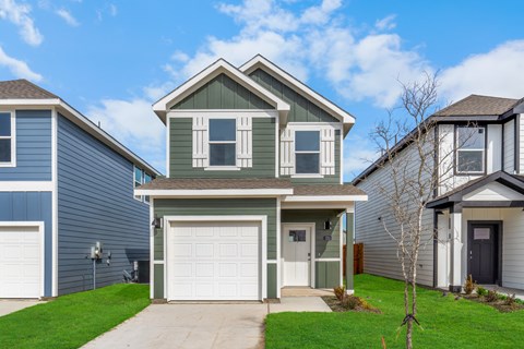 A house with a grey garage door is in front of two other houses.