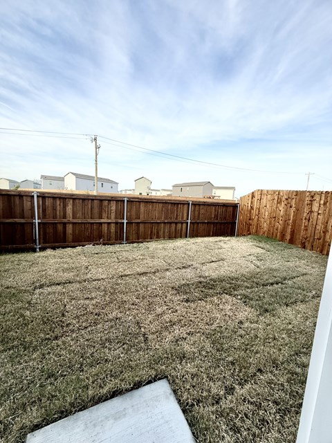 A backyard with a wooden fence and a small patch of grass.