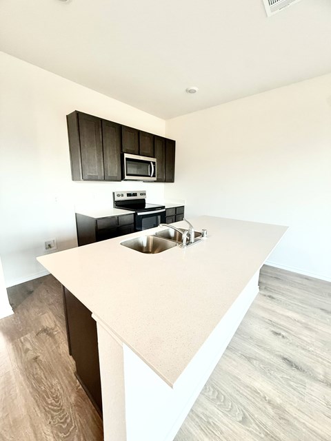 A kitchen with a white countertop and black cabinets.
