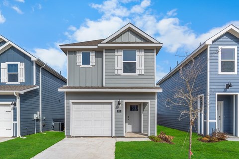 A house with a grey garage door is in front of two other houses.
