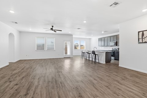 A spacious room with wooden flooring and a ceiling fan.