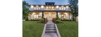 A modern house with a front yard and a set of stairs leading to the entrance.