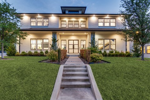 A modern house with a front yard and a set of stairs leading to the entrance.