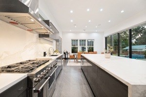 A modern kitchen with a long counter and a stove top oven.