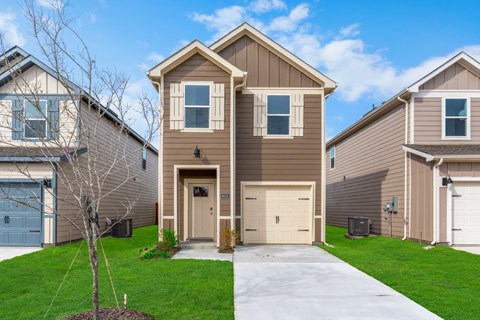 A brown house with a white garage door is in front of a blue sky.